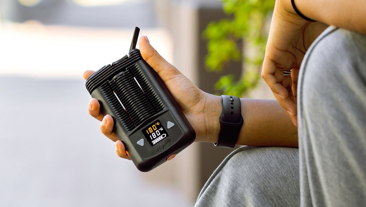 Tips For Choosing Best Weed Pens To Puff In: A closeup of young man's hands holding a big portable vaporizer with temperature settings