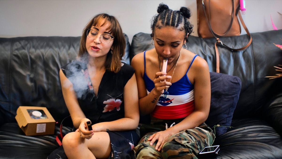 Tips For Choosing Best Weed Pens To Puff In: Two young women sitting on a couch ans smoking vape pens